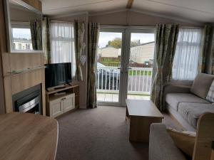 a living room with a couch and a television at 208 Holiday Resort Unity Brean 3 bed entertainment passes included in Brean