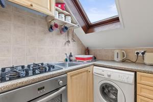 a kitchen with a washing machine and a sink at Cosy Flat In London in Ealing