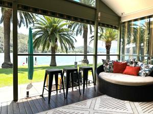 Eine überdachte Veranda mit Sofa und Hockern in der Unterkunft River Run in Wisemans Ferry