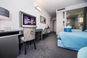 1 dormitorio con 1 cama y escritorio con TV en Hotel Arupinum, en Rovinj