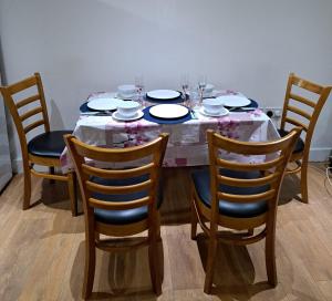 - une table avec des chaises, des assiettes et des verres à vin dans l'établissement Simply Relax,1 Eastham London, à Londres