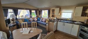 een keuken en een woonkamer met een bank en een tafel bij Bewles Caravan in Rhyl