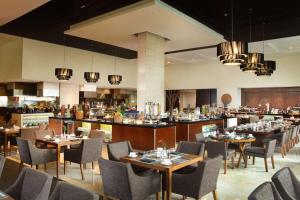 a restaurant with tables and chairs and a bar at Hilton Bandung in Bandung