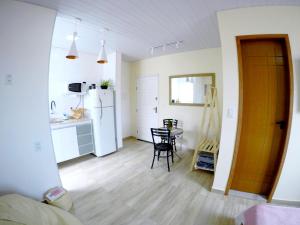 a kitchen with a table and a white refrigerator at Suítes do Cabo in Arraial do Cabo