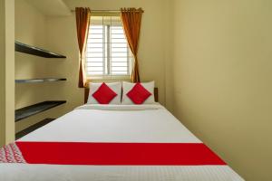 a bedroom with a white bed with red pillows at Motel Magic in Coimbatore