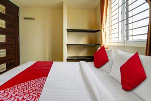 a bedroom with a bed with red and white pillows at Motel Magic in Coimbatore