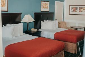 a hotel room with two beds with red sheets at Victorian Inn & Suites in Nacogdoches