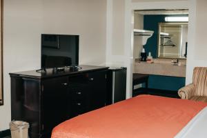 a room with a bed and a small kitchen with a kitchen at Victorian Inn & Suites in Nacogdoches