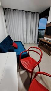 una camera con una sedia rossa, un letto e una TV di Maraca Beach Residence 1 apartamento 401 a Porto De Galinhas