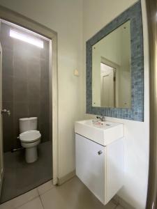 a bathroom with a toilet and a sink and a mirror at The 8 House – Surabaya City Center in Surabaya