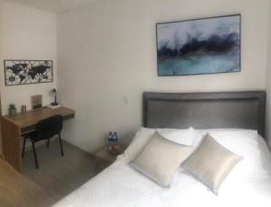 een slaapkamer met een bureau en een bed met witte kussens bij Hermoso Apartamento Chapinero in Bogota