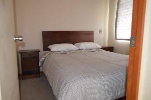 Schlafzimmer mit einem Bett und einem Kopfteil aus Holz in der Unterkunft Katri apart in Temuco