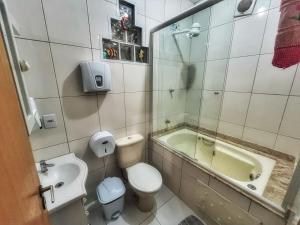 een badkamer met een bad, een toilet en een wastafel bij Tô na Guarda Hostel in Palhoça