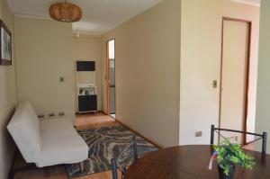 ein Wohnzimmer mit einem weißen Stuhl und einem Tisch in der Unterkunft Katri apart in Temuco