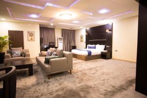 een hotelkamer met een bed en een bank en stoelen bij ED&DRE Luxuria Hotel in Ibadan