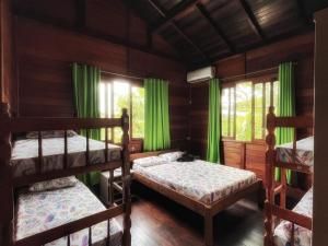 1 Schlafzimmer mit 2 Etagenbetten und grünen Vorhängen in der Unterkunft Tô na Guarda Hostel in Palhoça