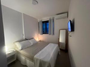 Habitación blanca con cama y TV en Novíssimo, 500m Praia, Garagem, Vista - Luzes do Arrebol, en Maceió