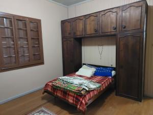 a small bedroom with a bed and wooden cabinets at Colônia da Nona Angélica in Farroupilha