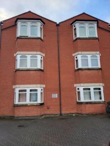 a red brick building with white windows on a street at Modern 2 Bed Apartment - Sleeps up to 5 - Coventry - Business and Leisure Stays in Coventry