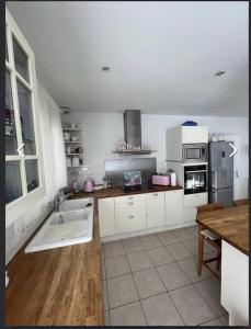 a kitchen with white cabinets and a wooden floor at maison tout confort in Saint-Vivien-de-Médoc