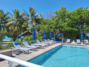 a group of chairs and a swimming pool with blue umbrellas at Beach House Lodge 