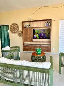 a living room with green chairs and a tv at Casa Encanto das Dunas in Santo Amaro