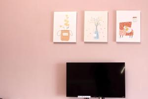 富里鄉的住宿－低調民宿，粉红色的墙上有三幅艺术作品,配有电视