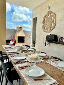 a long wooden table with plates and glasses on it at Casa Encanto das Dunas in Santo Amaro