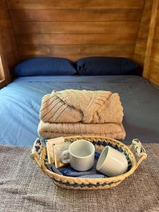 a basket with towels and cups on a bed at Glamping Cabanas do Estaleiro in Balneário Camboriú