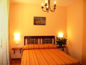 a bedroom with a bed with an orange bedspread and two lamps at DolceVitaSorrento Guest House in Sorrento