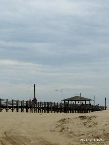 ein Pier am Strand mit Leuten darauf in der Unterkunft Cabana da barra in Içara