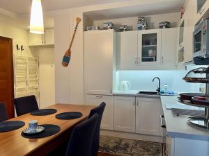 a kitchen with a wooden table and a kitchen with white cabinets at Wakacyjnie Jurata Nad Zatoka in Jurata