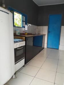 a kitchen with a stove and a blue door at Cantinho do sossego in Macaé