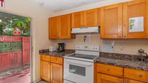 a kitchen with wooden cabinets and a white stove top oven at Crocodhouse in Fort Lauderdale