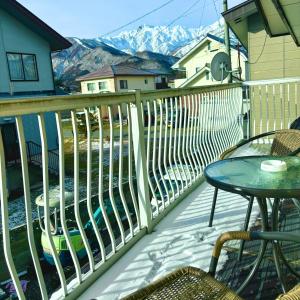 a balcony with a table and chairs and mountains at Snow Fever - Clan in Hakuba