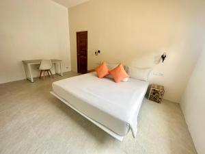 a white bed with orange pillows in a room at Oh'lala luxury pool villas in Thongsala