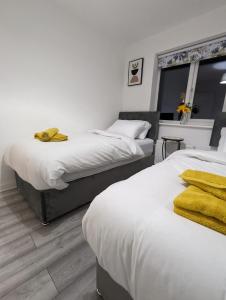 um quarto com 2 camas com toalhas amarelas em Freshen-up stays Doncaster em Bentley