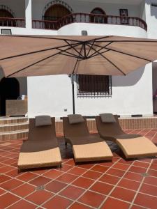 two lounge chairs and an umbrella on a tile floor at La torrecita in Barbosa