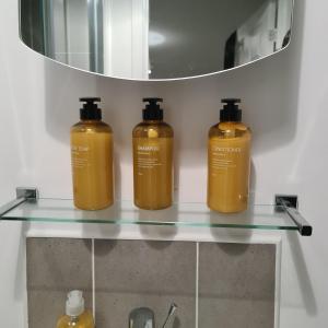 trois bouteilles sur une étagère en verre avec un miroir dans l'établissement Freshen-up stays Doncaster, à Bentley