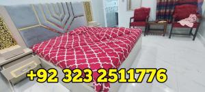 Bett mit einer roten Bettdecke in einem Zimmer in der Unterkunft Elegant Guest House Karachi in Karatschi