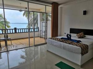 a bedroom with a bed and a view of the ocean at Cool Beach Hotel in Hikkaduwa
