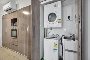 a small kitchen with a sink and a washing machine at Stunning 2 Bedroom Self Contained City Apartment in Mackay