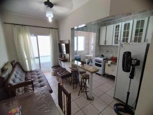 een keuken en een woonkamer met een bank en een koelkast bij Na quadra da praia - Apto Completo Próximo a Estátua de Iemanjá - Vaga de Garagem e Wi-Fi in Praia Grande