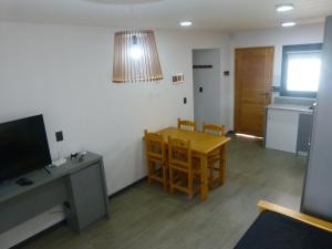 ein Wohnzimmer mit einem Tisch, Stühlen und einem TV in der Unterkunft Departamento RUKA-9 in San Martín de los Andes