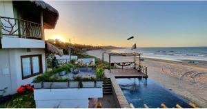 a building on the beach with the ocean in the background at Vila Caetanos in Amontada