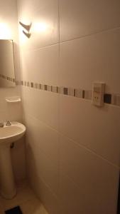 ein weißes Badezimmer mit einem Waschbecken und einem Spiegel in der Unterkunft 3Reyes in Necochea