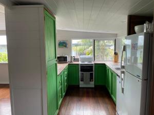 a kitchen with green cabinets and a white refrigerator at Good Vibes, 18 East Street in Crescent Head
