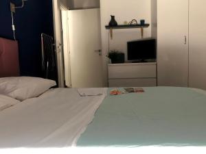 1 dormitorio con 1 cama blanca grande y TV en Green Suite Pavia en Pavia