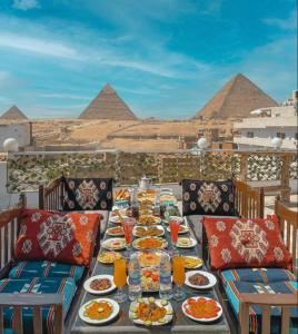 een tafel met borden met voedsel met piramides op de achtergrond bij Sphinx golden gate pyramids view in Caïro