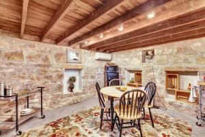 a dining room with a table and chairs and a stone wall at The Rock House Hideaway - TANK HOUSE in Fredericksburg